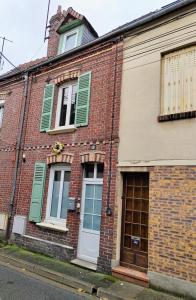 un viejo edificio de ladrillo con persianas verdes. en LA PETITE MAISON en Beauvais