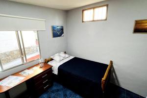 1 dormitorio con cama, escritorio y ventana en Cómoda habitación privada 2 personas FULL BED & FULL SOFA CAMA en Puerto Ayora