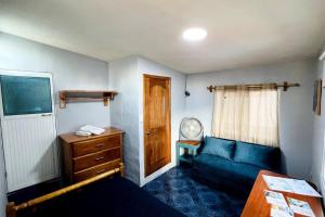 a small bedroom with a blue couch and a window at Cómoda habitación privada 2 personas FULL BED & FULL SOFA CAMA in Puerto Ayora