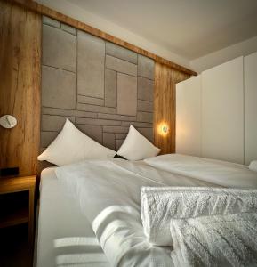 a bedroom with a white bed with a large headboard at mountain view in Piesendorf