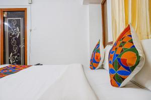 FabHotel Lake View في بيون: غرفة نوم مع سريرين مع وسائد ملونة