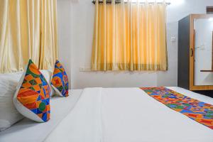 1 dormitorio con cama blanca y almohadas coloridas en FabHotel Lake View, en Pune