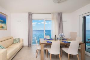 a living room with a dining room table with a view of the ocean at Epetium Beach Villa in Split +60 photos