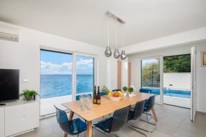 a dining room with a table and views of the ocean at Epetium Beach Villa in Split