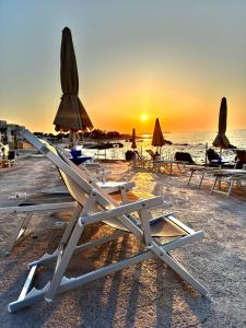 Hotel Riva Del Sole في جيوفيناتسو: مجموعة من كراسي الصالة والمظلات على الشاطئ