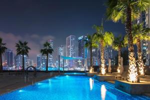 a swimming pool with a city skyline at night at Modern 2 Bedroom Suite Stunning view Sparkle Tower in Dubai