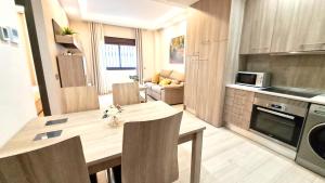 cocina y sala de estar con mesa de madera y sillas en Apartamentos Vacacionales Joctis, Bajo B en Fuengirola