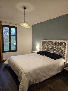Un dormitorio con una gran cama blanca y una ventana en Le refuge de Loire, en Montrelais