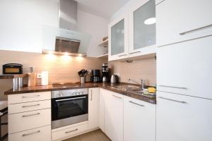 een keuken met witte kasten en een spoelbak bij Kurparkresidenz Baabe Penthouse Windjammer in Baabe