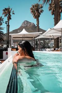 una mujer en una piscina con palmeras en The Bay Hotel, en Ciudad del Cabo