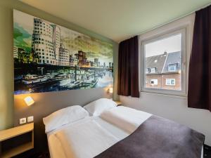 a bed in a room with a large window at B&B Hotel Düsseldorf City-Süd in Düsseldorf