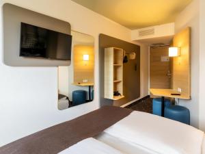 ein Hotelzimmer mit einem Bett und einem Flachbild-TV in der Unterkunft B&B Hotel Düsseldorf City-Süd in Düsseldorf
