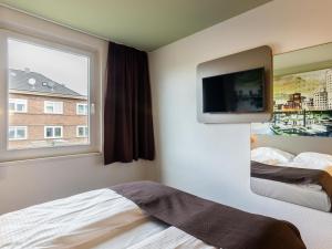 Schlafzimmer mit einem Bett, einem TV und einem Fenster in der Unterkunft B&B Hotel Düsseldorf City-Süd in Düsseldorf