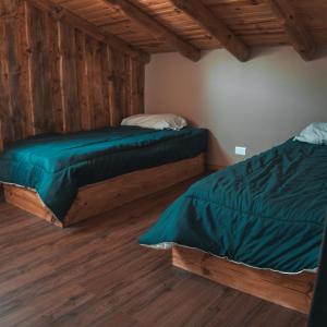 two beds in a room with wooden floors at Cabañas El Arriero Lodge in Manzano Amargo