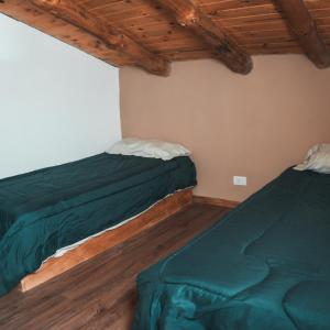 two beds in a room with wooden ceilings at Cabañas El Arriero Lodge in Manzano Amargo