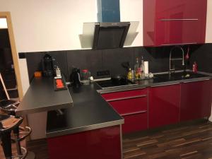 a kitchen with red cabinets and a black counter top at Casa DelSillie ... Magnet Pin Welcome in Bochum +9 photos