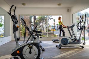 Una mujer está haciendo ejercicio en dos bicicletas estáticas en un gimnasio en Monarque Club Rivage - VV en Monastir