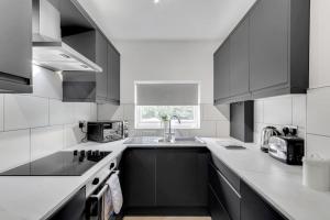 a kitchen with black and white cabinets and a sink at 1bed apartment with parking close to City Centre in Thorpe Saint Andrew