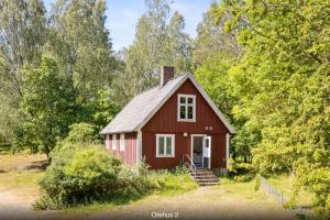 una casa roja en un campo con árboles en Orehus - Country side cottage with garden en Sjöbo
