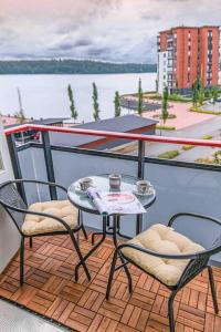 een tafel en 2 stoelen op een balkon met uitzicht op het water bij Light modern Pallo apartment by the lake Saimaa in Lappeenranta