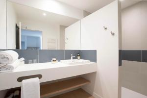 La salle de bains blanche est pourvue d'un lavabo et d'un miroir. dans l'établissement LOGIS LES CEPAGES / RESTAURANT LE RAISIN, à Pont-de-Vaux