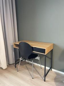 einen Schreibtisch mit einem schwarzen Stuhl neben einem Vorhang in der Unterkunft Light modern Pallo apartment by the lake Saimaa in Lappeenranta
