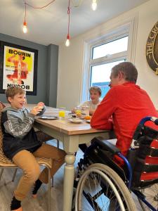 a man sitting at a table with a boy in a wheelchair at Artypophouse Unique home to create unique memories in Bersted