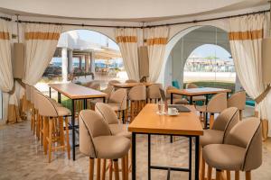 un restaurant avec des tables, des chaises et des fenêtres dans l'établissement Monarque Club Rivage - VV, à Monastir
