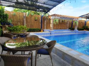 eine Terrasse mit Tischen und Stühlen neben einem Pool in der Unterkunft TRD Private Hotspring Resort in Pansol
