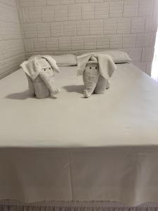 two stuffed elephants sitting on top of a bed at Chalé Apart Hotel in Bonito