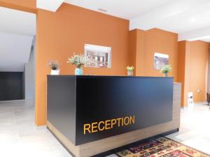 a reception desk in a lobby with orange walls at MIK Hotel Korce in Korçë