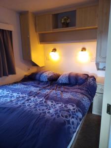a bed with a blue comforter in a bedroom at De Boerenskuur..chalet.. in Assendelft