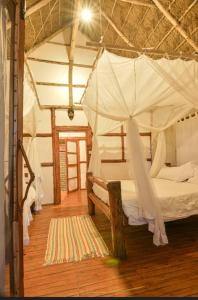 1 dormitorio con cama con dosel y suelo de madera en Kazinga Wilderness Lodge, en Katunguru
