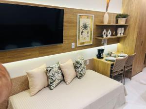 a living room with a couch with a flat screen tv at Makia Flat Muro Alto in Porto De Galinhas