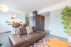a living room with a brown couch and a table at Hypercentre: apartment near station with parking in Lille