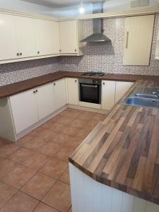 a kitchen with white cabinets and a wooden counter top at Stylish 3-Bed Gem in Romiley Newly Renovated, En Suite Comfort, Courtyard Charm, and Effortless Parking in Romiley