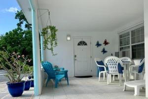 een terras met blauwe en witte stoelen en een deur bij SUITE 1, Blue Pavilion - Beach, Airport Taxi, Concierge, Island Retro Chic in West Bay