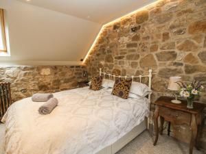 a bedroom with a bed with a stone wall at Corn House in Plaish