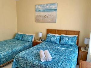 a bedroom with two beds with blue comforter at SUITE 3, Blue Pavilion - Beach, Airport Taxi, Concierge, Island Retro Chic in West Bay