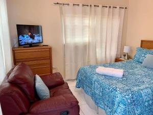 ein Schlafzimmer mit einem Bett und einer Couch und einem Fernseher in der Unterkunft SUITE 4, BLUE PAVILION - Steps to BEACH in West Bay