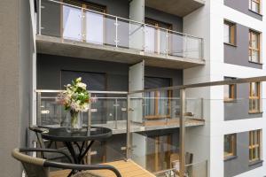 un balcón con una mesa y un jarrón de flores en Tasteful Beige Apartment with Parking by Renters en Poznan