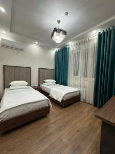 two beds in a bedroom with green curtains at Hello Dushanbe Hostel in Dushanbe