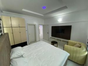 Schlafzimmer mit einem Bett und einem Flachbild-TV in der Unterkunft MilesVilla Apartments in Enugu