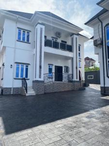 ein weißes Haus mit einer Einfahrt davor in der Unterkunft MilesVilla Apartments in Enugu