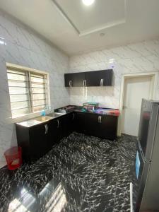 a kitchen with black cabinets and a black floor at MilesVilla Apartments in Enugu