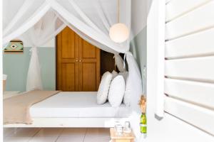 um quarto com uma cama de dossel e almofadas brancas em Vila Charme em Jericoacoara