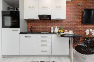 a kitchen with white cabinets and a brick wall at Bright & Cozy Studio near Metro Marymont by Renters in Warsaw