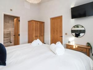 a bedroom with a white bed with a tv on the wall at Robins Nest in York