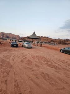 three cars parked in a dirt field with a gazebo at Harir Rum luxury camp in Wadi Rum