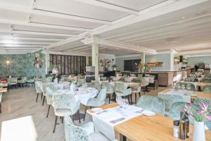 une salle à manger avec des tables et des chaises blanches dans l'établissement Van der Valk Hotel Barcarola, à Sant Feliu de Guíxols